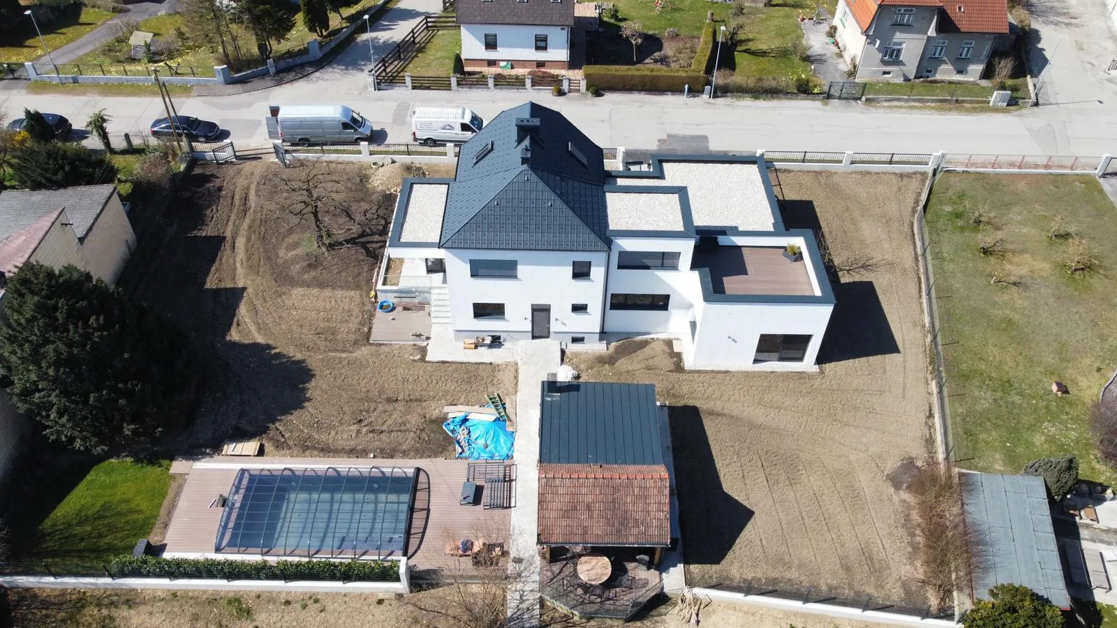 Drohnenaufnahme eines Einfamilienhauses mit anthrazitfarbenem Dach und Pool