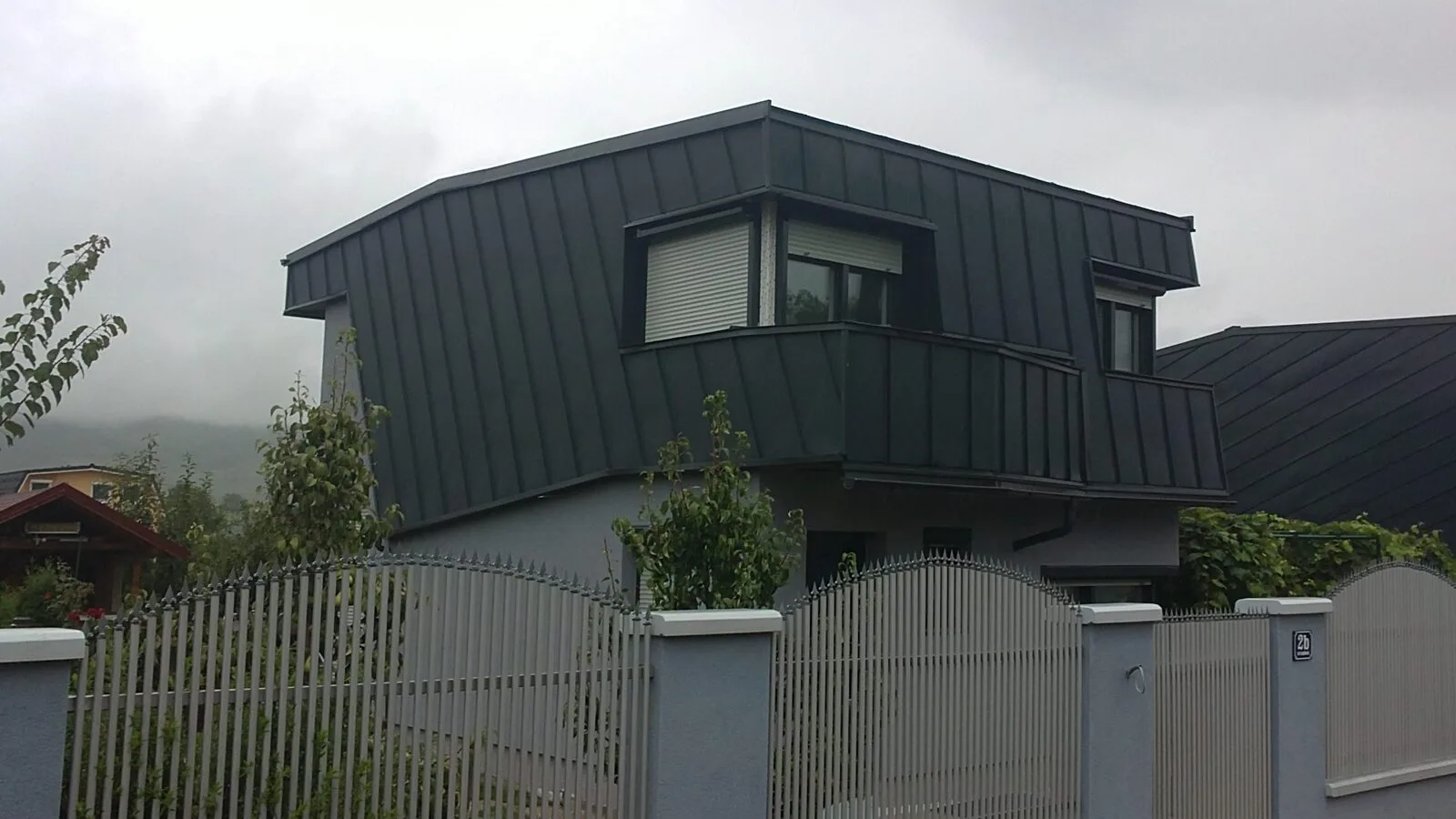 Wohnhaus mit dunkel verkleideter Dachgaube und Blechverkleidung